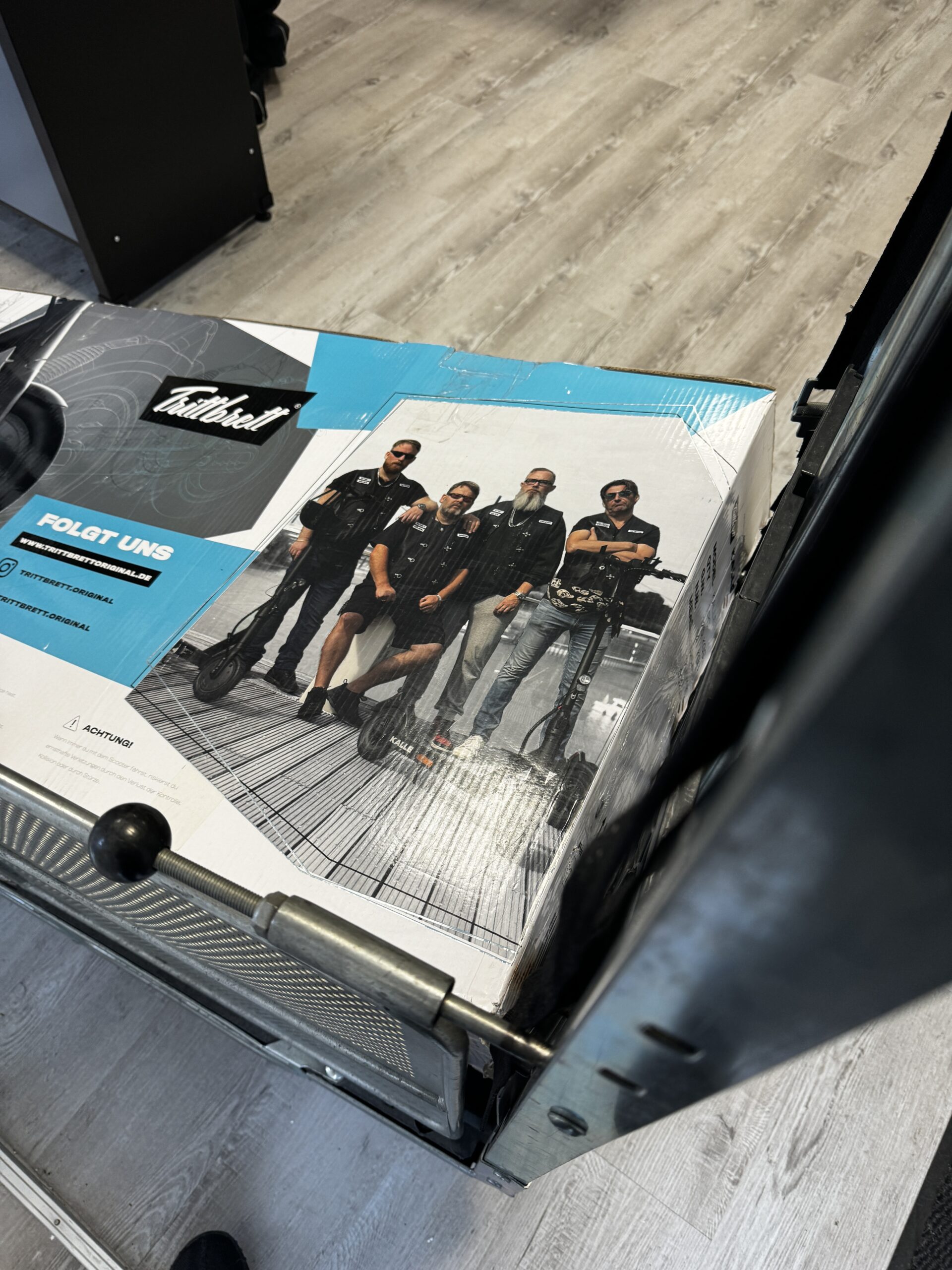 Gruppenmotiv der Trittbrett E-Scooter Kampagne auf der Verpackung mit Achim Hepp